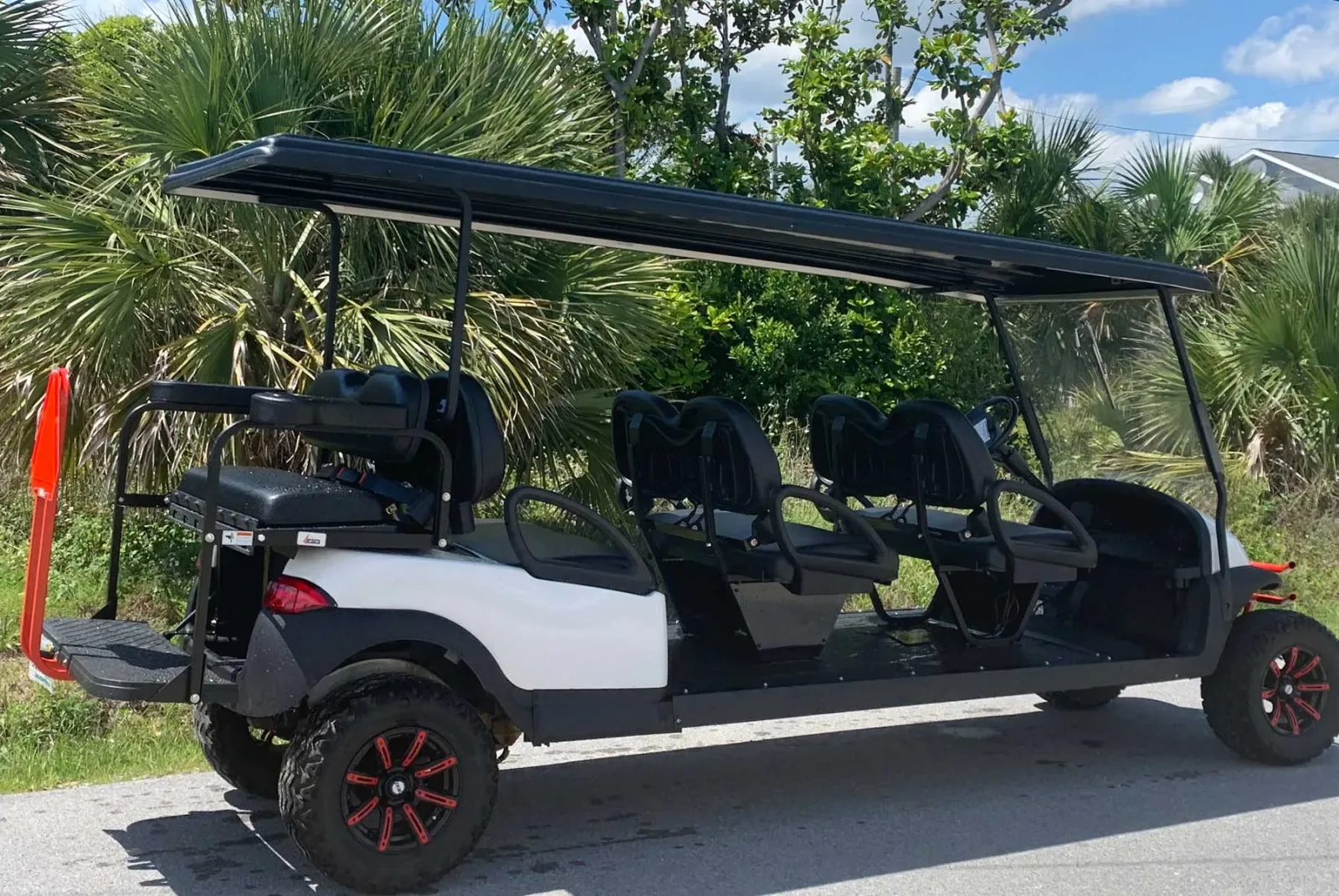White 8-passenger stretch golf cart with a black canopy and red wheels