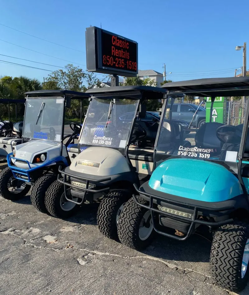 Golf carts lined up under the Classic Rentals 850-235-1519 sign