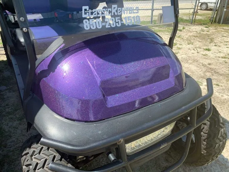 Purple metal-flake golf cart with Classic Rentals 850-235-1519 on the windshield